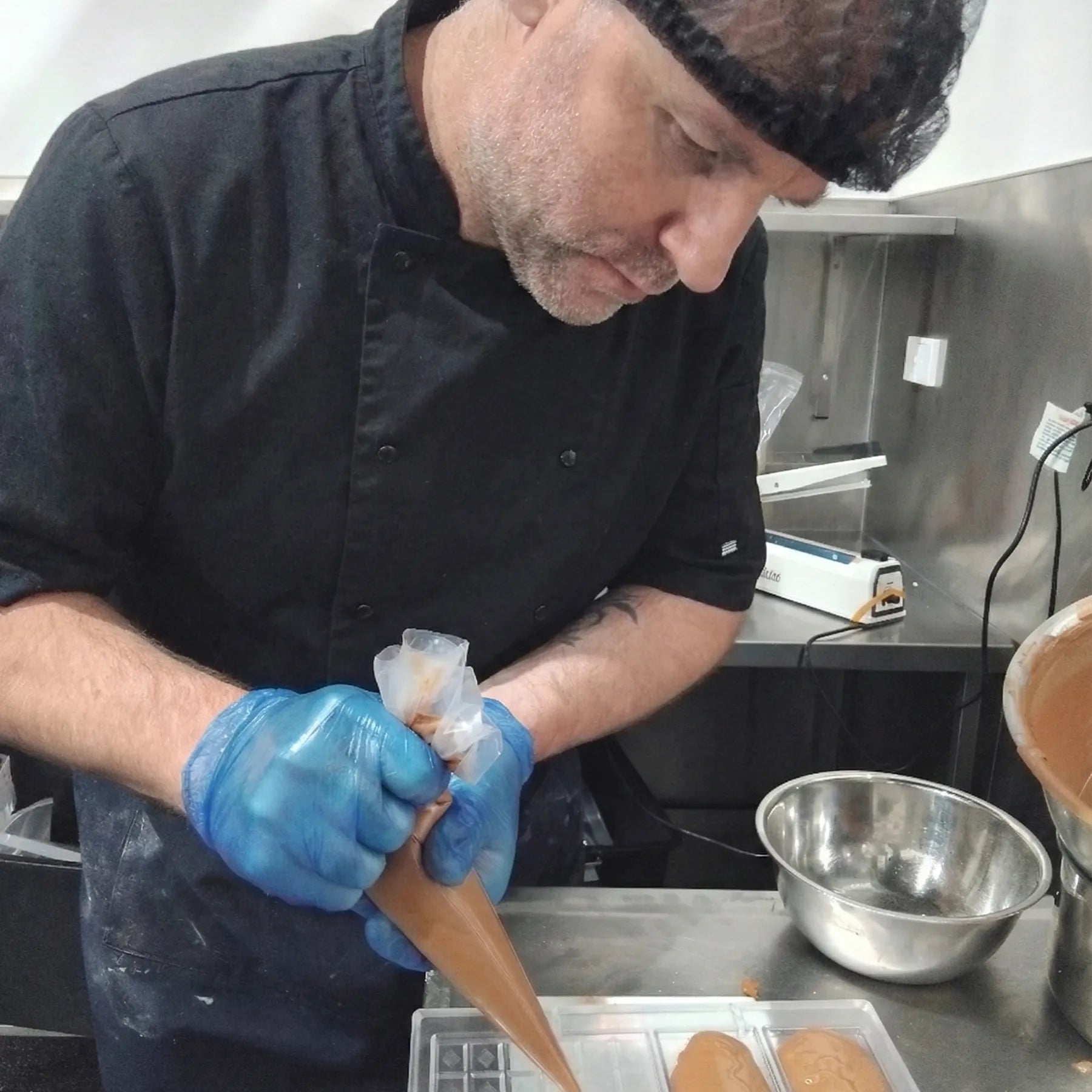 Wayne is piping chocolate into bar moulds in the chocolate kitchen